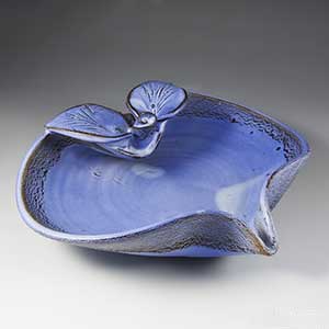 blue stoneware bowl decorated with a floral theme in the style of arne bang
